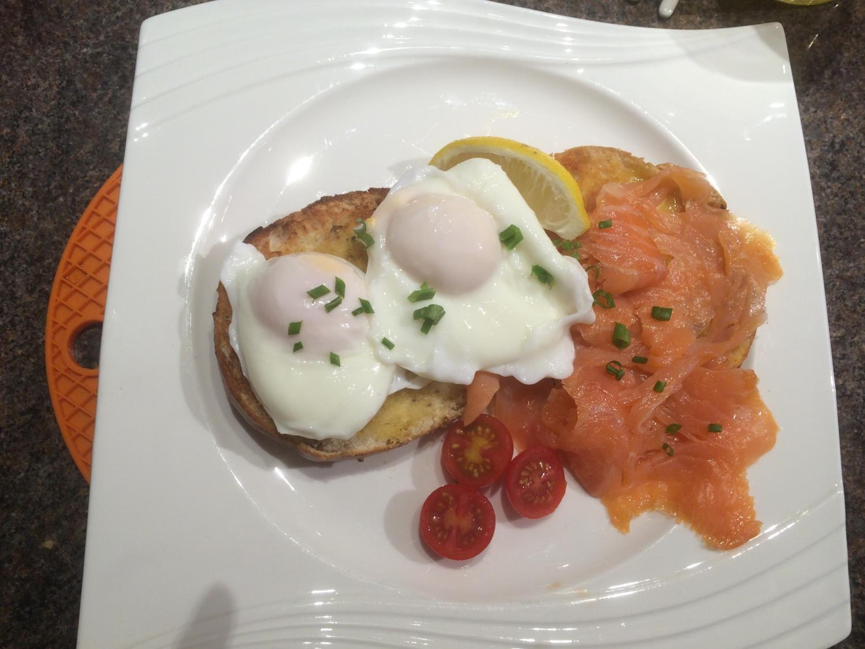 Un plato con huevos, salmón ahumado y tomates cherry.