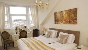 Une chambre à coucher avec un grand lit, un bureau, une chaise, une commode et un tableau accroché au mur.