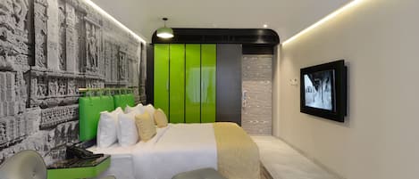 Un dormitorio moderno con una cama grande, detalles en verde, un mural y un televisor en la pared.
