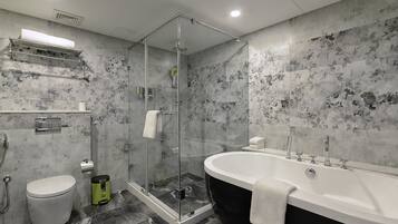 Un baño moderno con cabina de ducha de vidrio, bañera independiente y retrete.