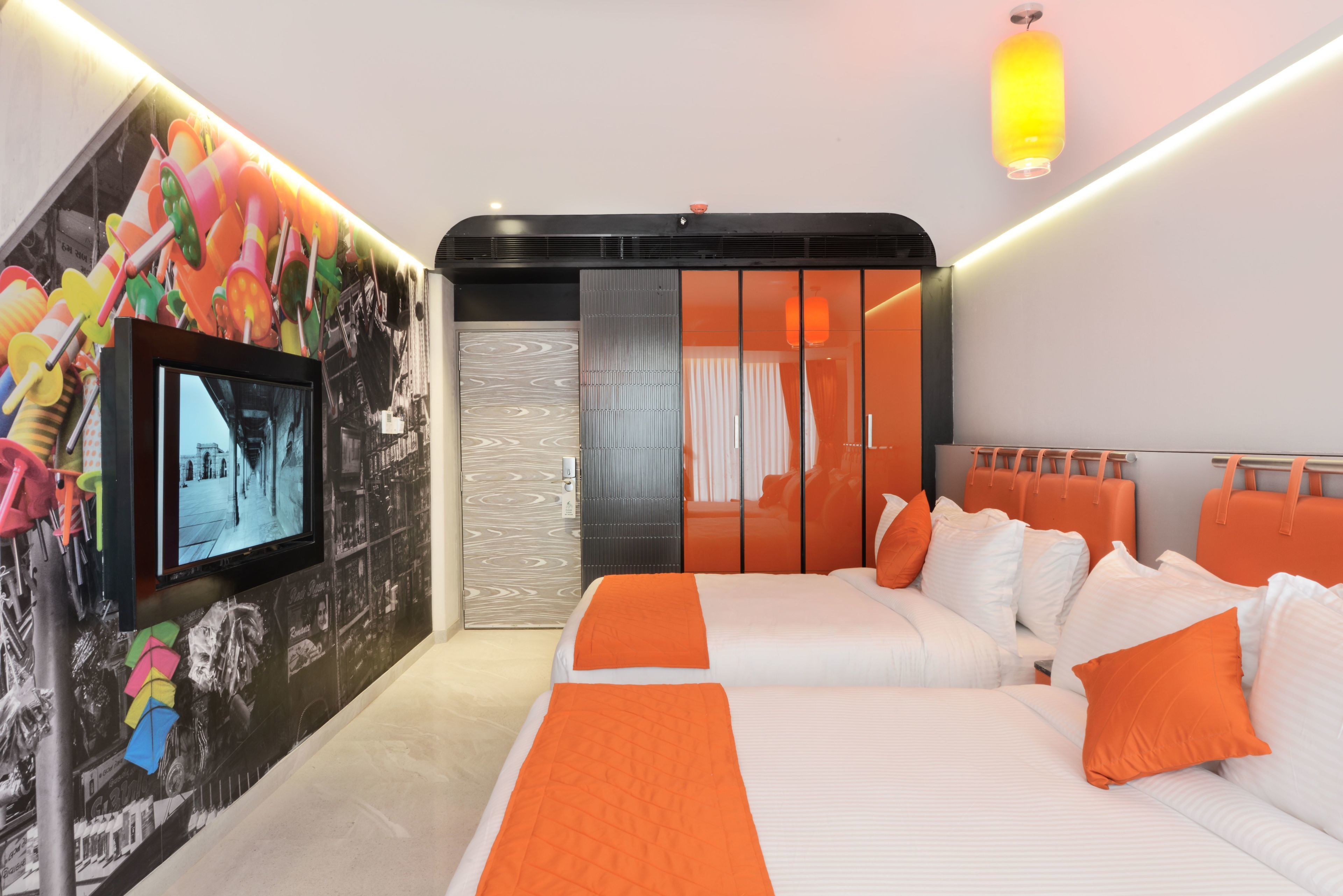 A modern hotel room with a large bed, a television, and a colorful mural on the wall.