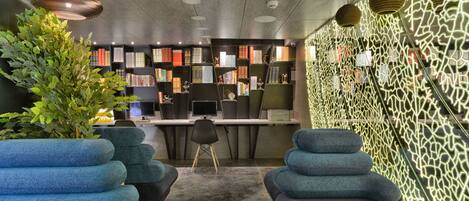 A modern library with bookshelves, seating areas, and a decorative wall.