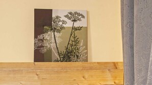 Une chambre d’hôtel avec un bureau en bois, un ordinateur portable affichant un graphique, un bol de fruits, une bouteille, une télécommande et un panneau sur lequel on peut lire : « Tout arrive pour une raison. »