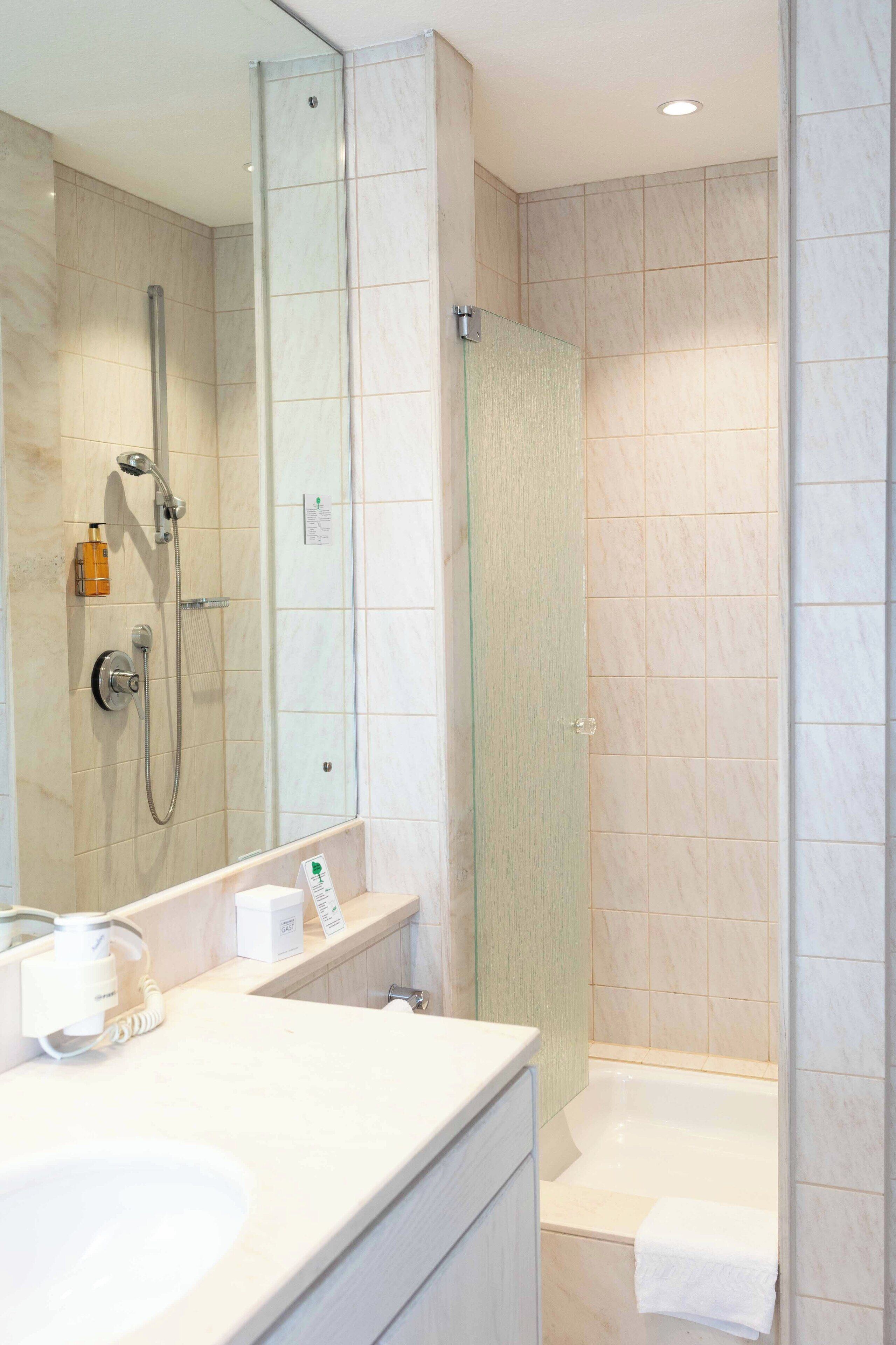 Un baño moderno con cabina de ducha de vidrio, un lavabo blanco y una bañera.