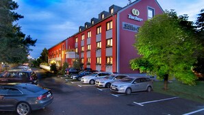 Un bâtiment rouge dont la façade porte les noms « Tucher » et « Schulze », avec un parking devant.
