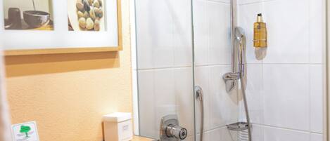 A bathroom with a glass shower enclosure, a towel rack, and a framed picture on the wall.