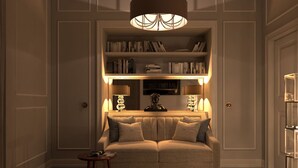 En hyggelig stue med en sofa, et lille sofabord, en bogreol og en dekorativ lampe.