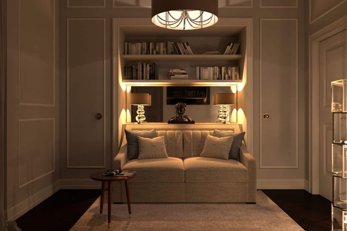 A cozy living room with a sofa, a small side table, a bookshelf, and a decorative lamp.