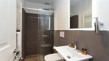 Une salle de bain moderne avec une douche à parois de verre, un lavabo blanc et un grand miroir.