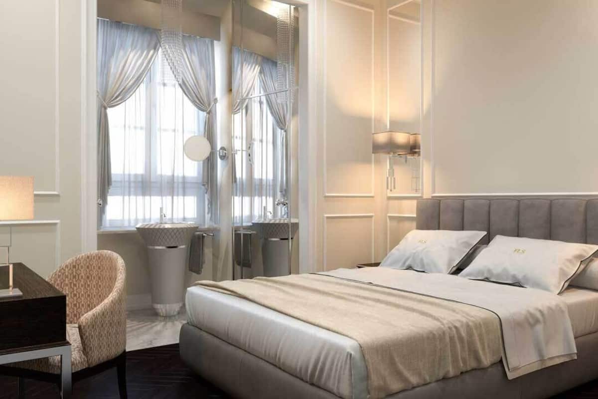 A modern bedroom with a large bed, a bedside table, a chair, and a window with curtains.