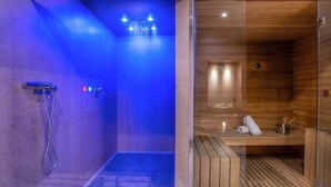 Et moderne spa med et badeområde i blåt lys og en træsauna.