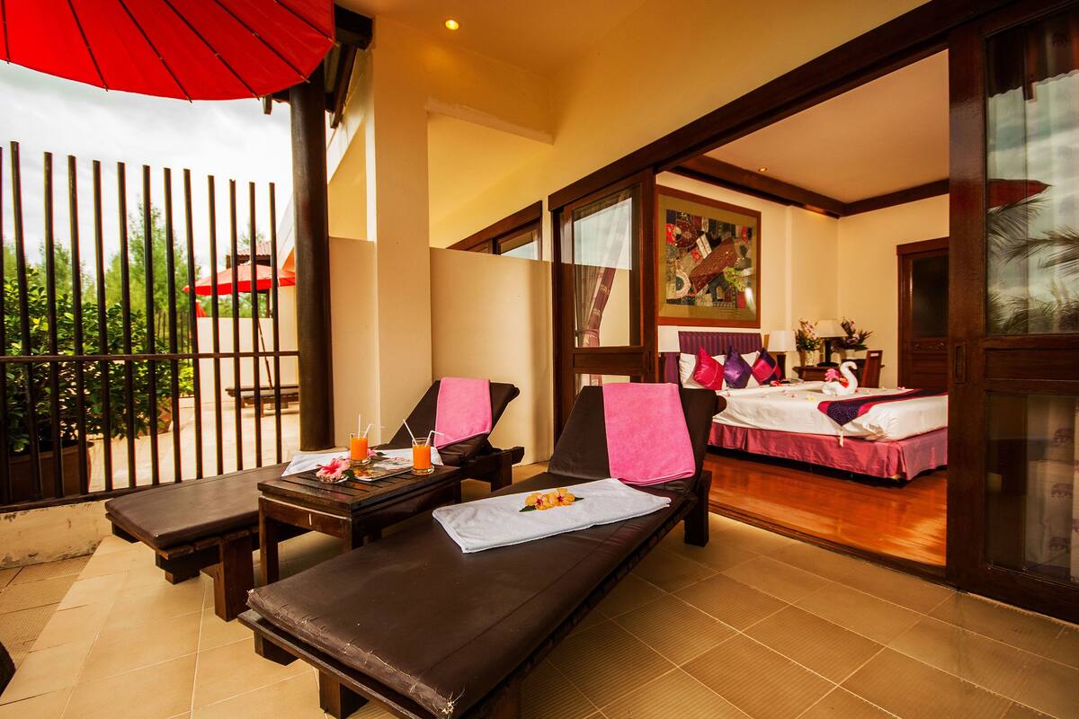 A room with two beds, a massage table, and a small table with a drink and fruit.