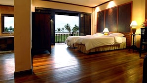 Una habitación de hotel con una cama grande, un escritorio y vistas a palmeras.