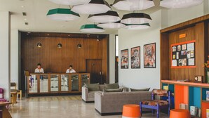 Un moderno hall de entrada con mostrador de recepción, sofás y un área de descanso colorida.