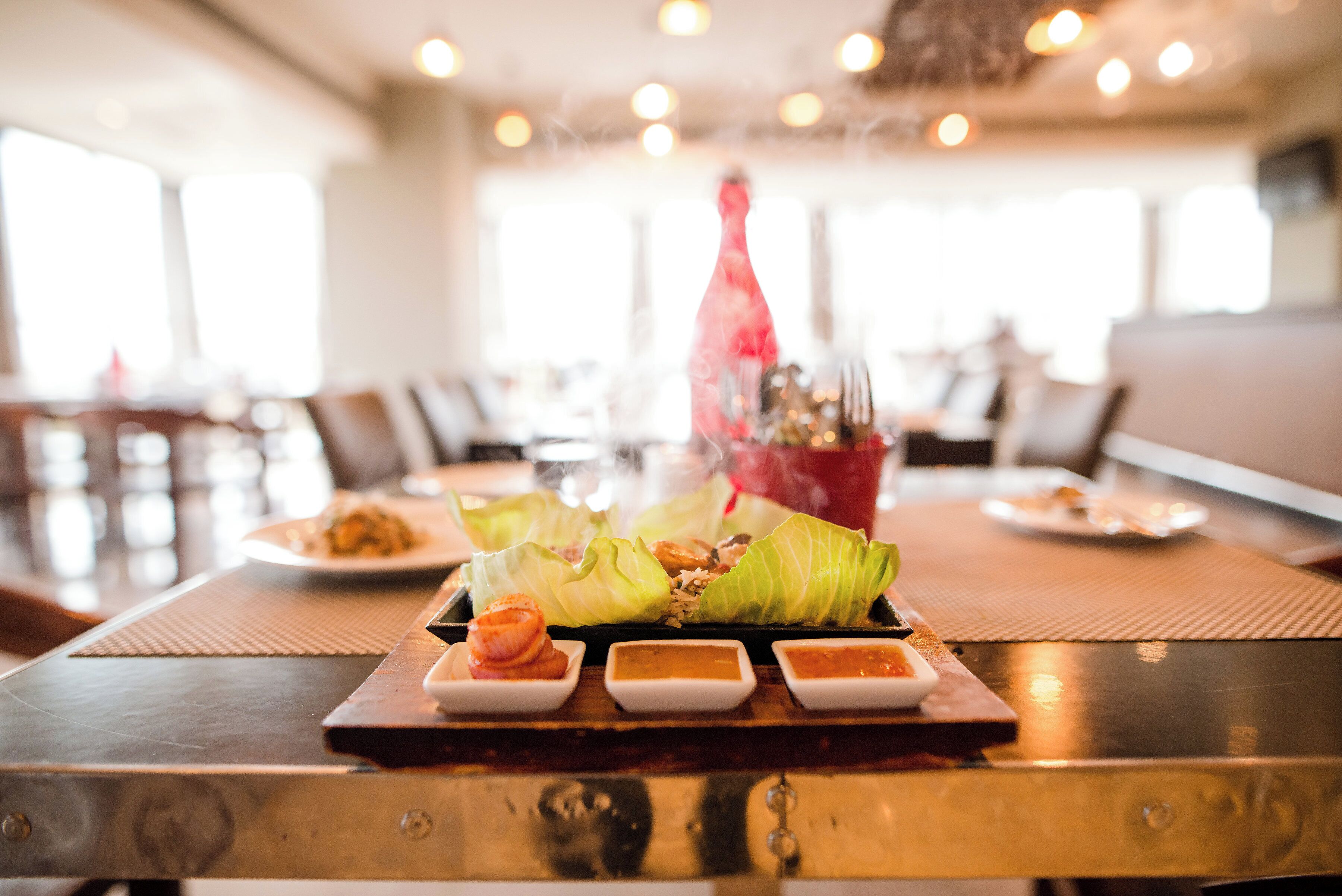 A dining table with a plate of food, including a wrapped item and small bowls of sauces.