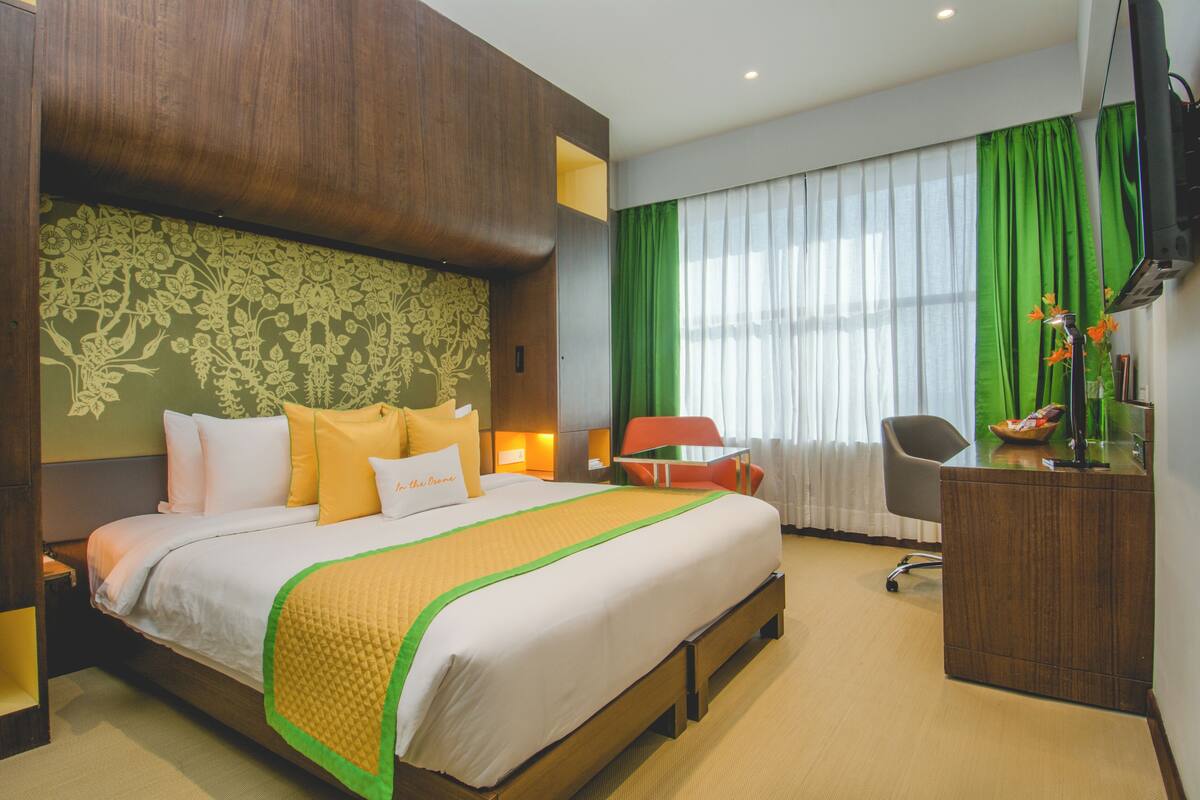 Una habitació d'hotel amb un llit gran, una taula de treball, una cadira i una televisió.