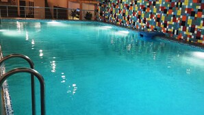 Una piscina interior con una pared de mosaicos coloridos y escaleras de metal.