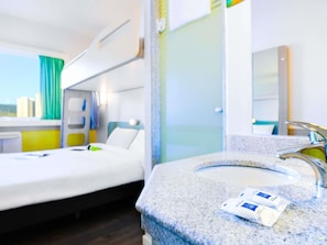A hotel room with a bed, a bathroom with a sink, and a window with curtains. - ibis budget Jundiai Shopping (Jundiai)