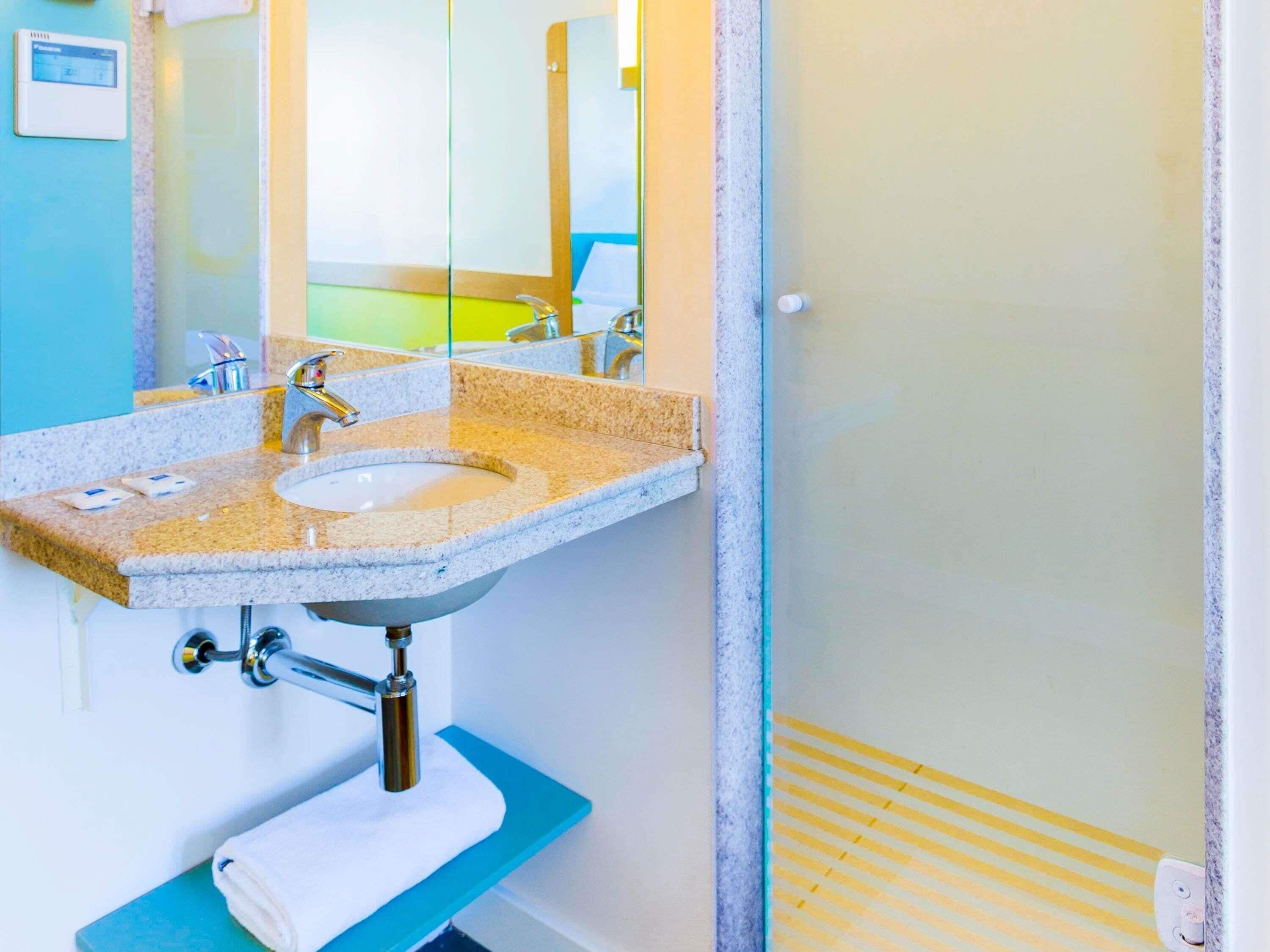 A bathroom with a granite countertop sink, a mirror, and a towel rack.
