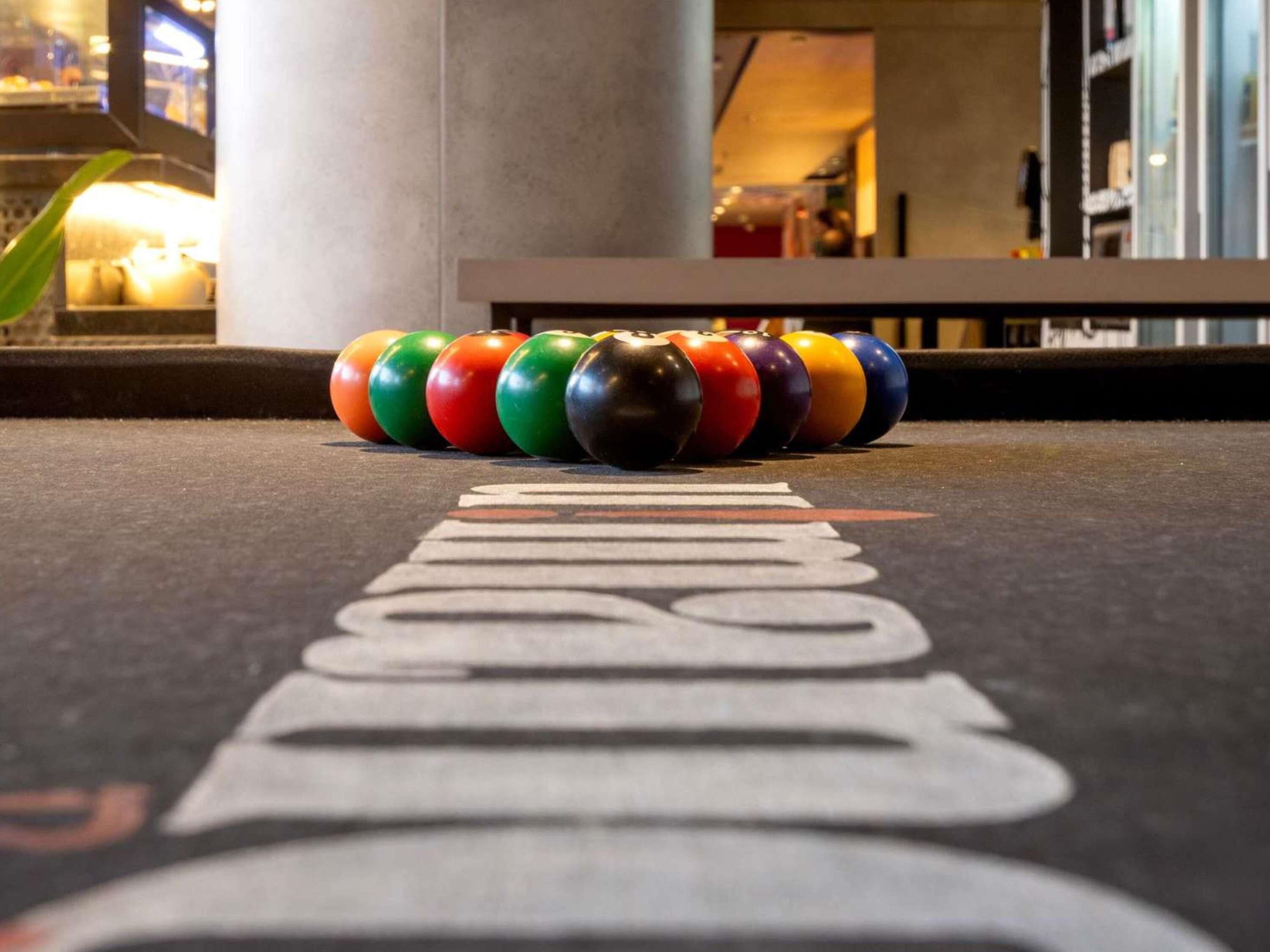 Bolera con una fila de bolos coloridos y una pista marcada con la palabra 'BOWLING'.