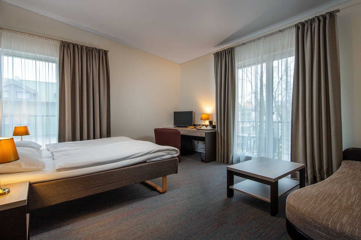 A hotel room with a bed, desk, chair, and a small table.