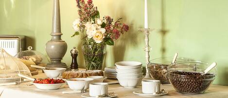A dining table with a lamp, a vase of flowers, and various dishes and utensils.