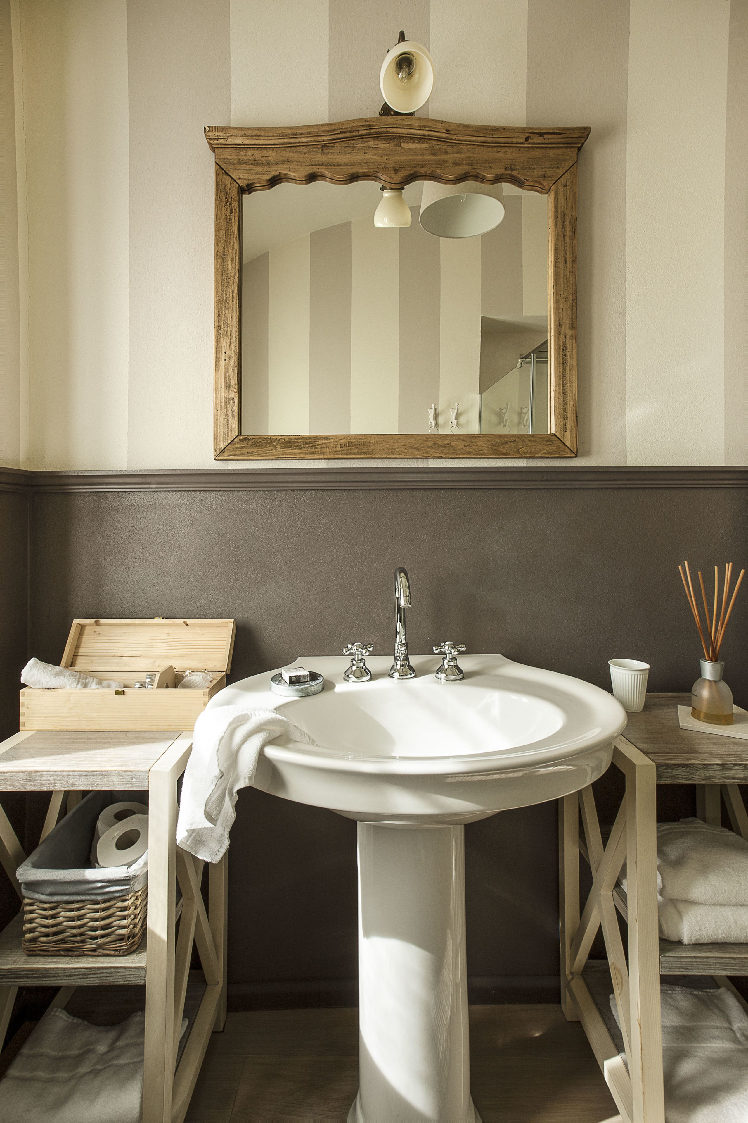 A bathroom with a white sink, wooden vanity, and a mirror with a wooden frame.