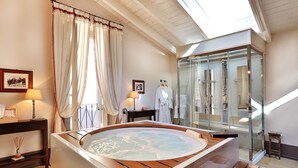 Une salle de spa équipée d’un bain à remous, d’une douche à parois de verre et d’un banc en bois.