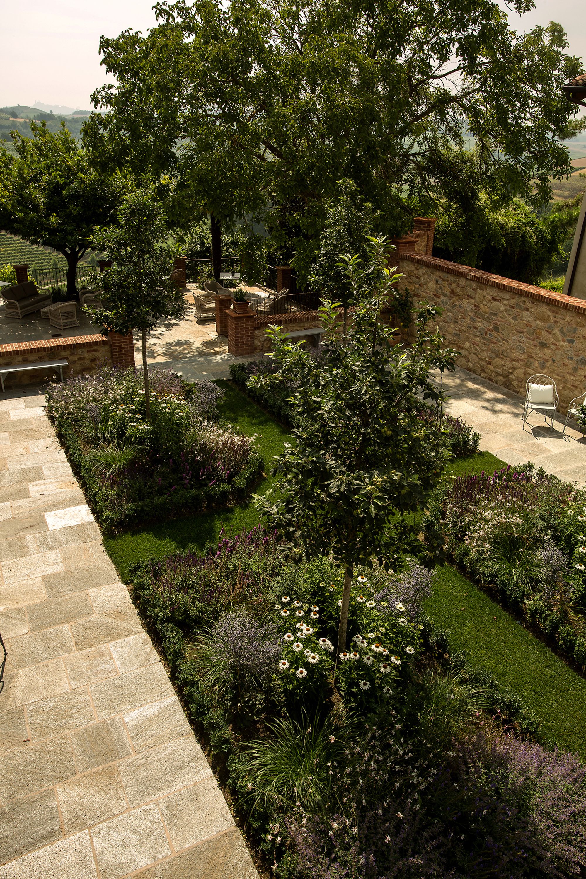 A landscaped garden with a stone pathway, seating area, and a stone wall.
