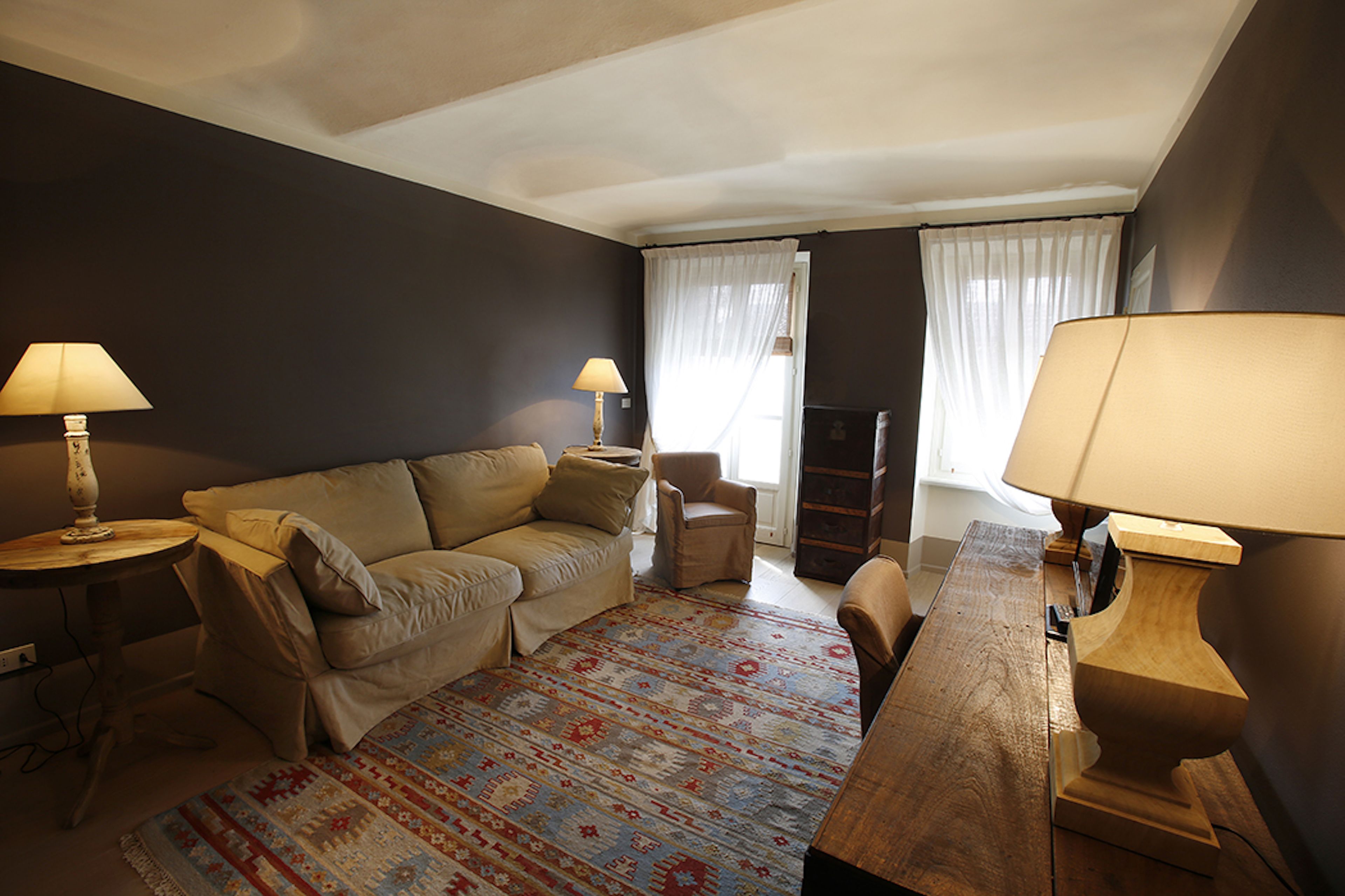 A living room with a sofa, armchairs, a wooden coffee table, and two lamps.
