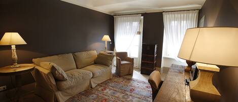 A living room with a sofa, armchairs, a wooden coffee table, and two lamps.