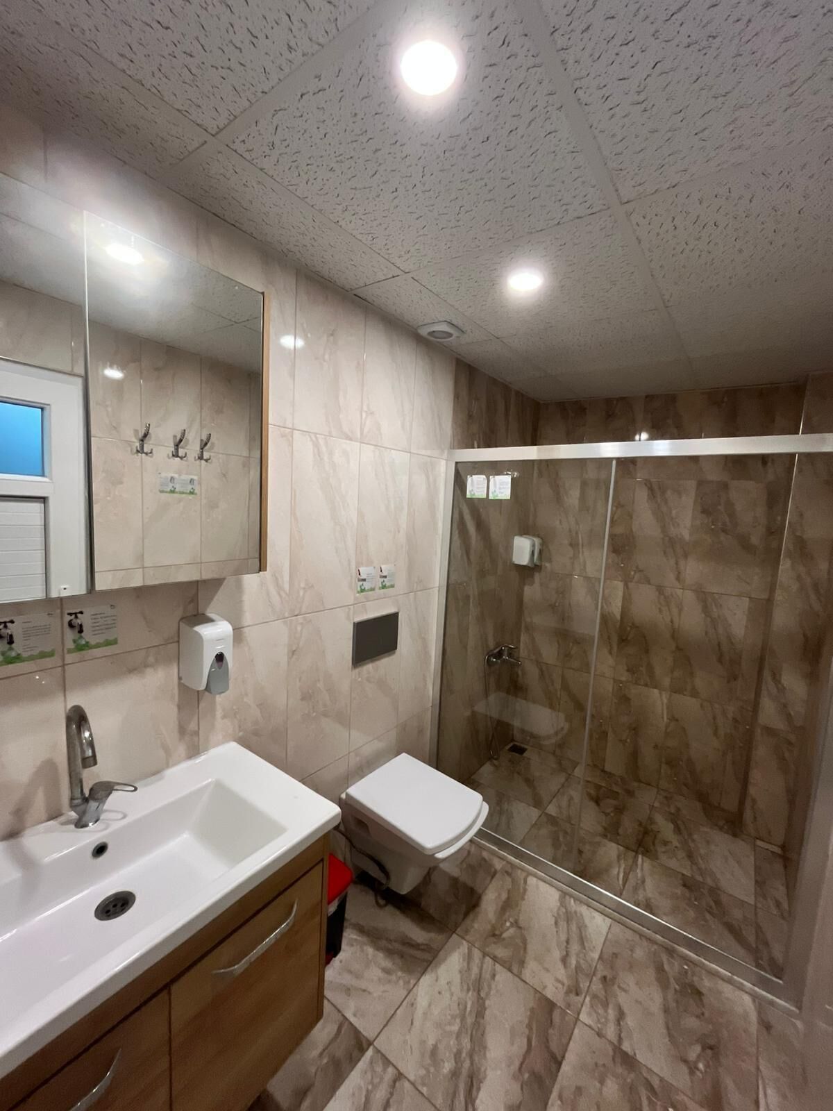 A bathroom with a sink, mirror, toilet, and a glass-enclosed shower.