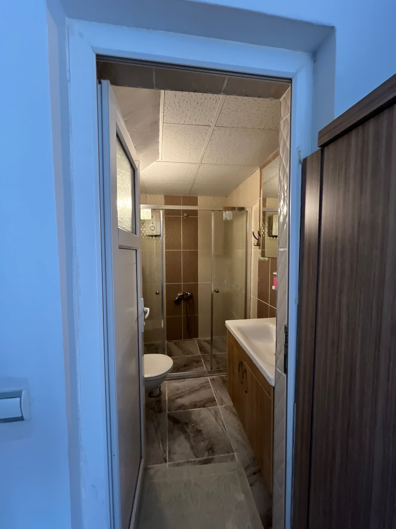Et badeværelse med brusebad, toilet og vaskemøbel.