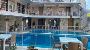 Hotel de varios niveles con piscina central, mobiliario exterior y balcones.