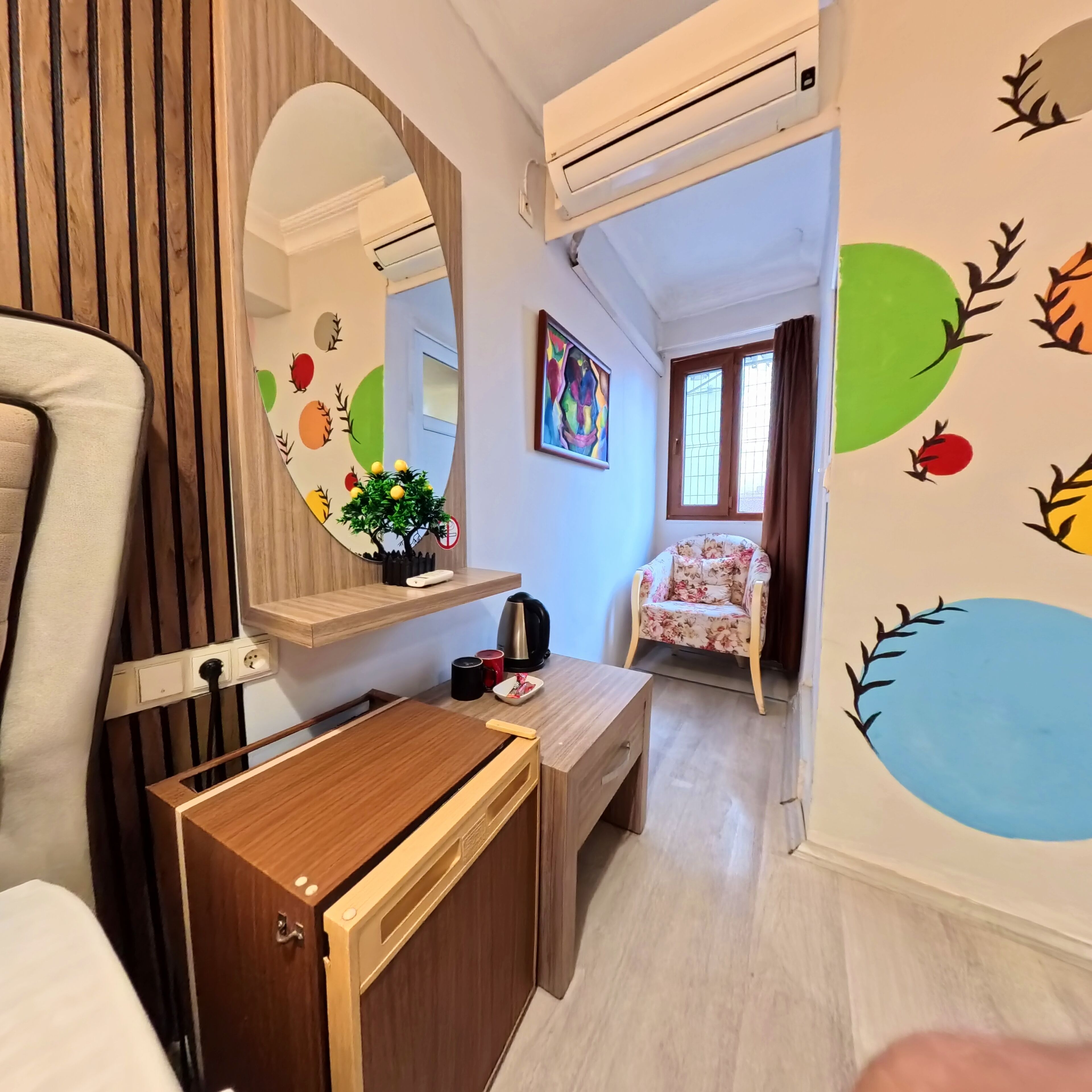 Una habitación pequeña con escritorio de madera, una silla, un espejo y una cama.