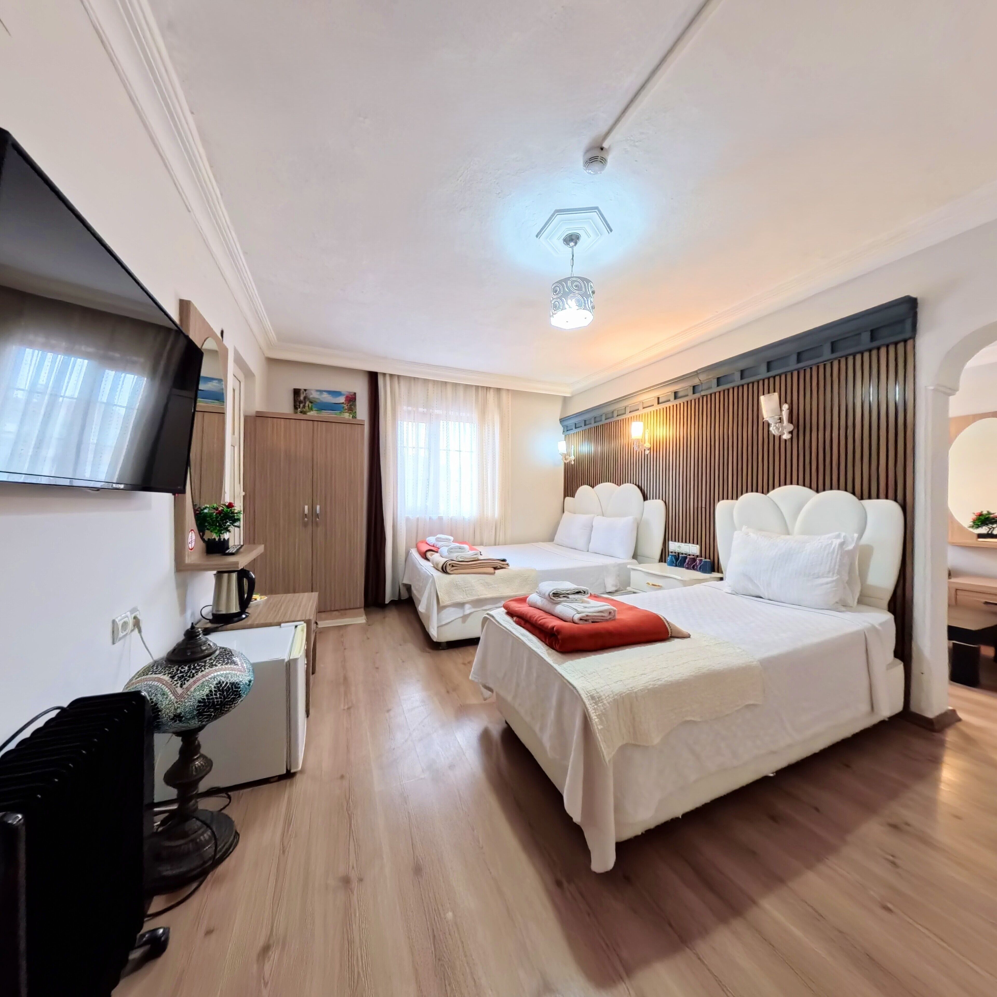 A hotel room with a bed, bedside table, TV, desk, and a wardrobe.