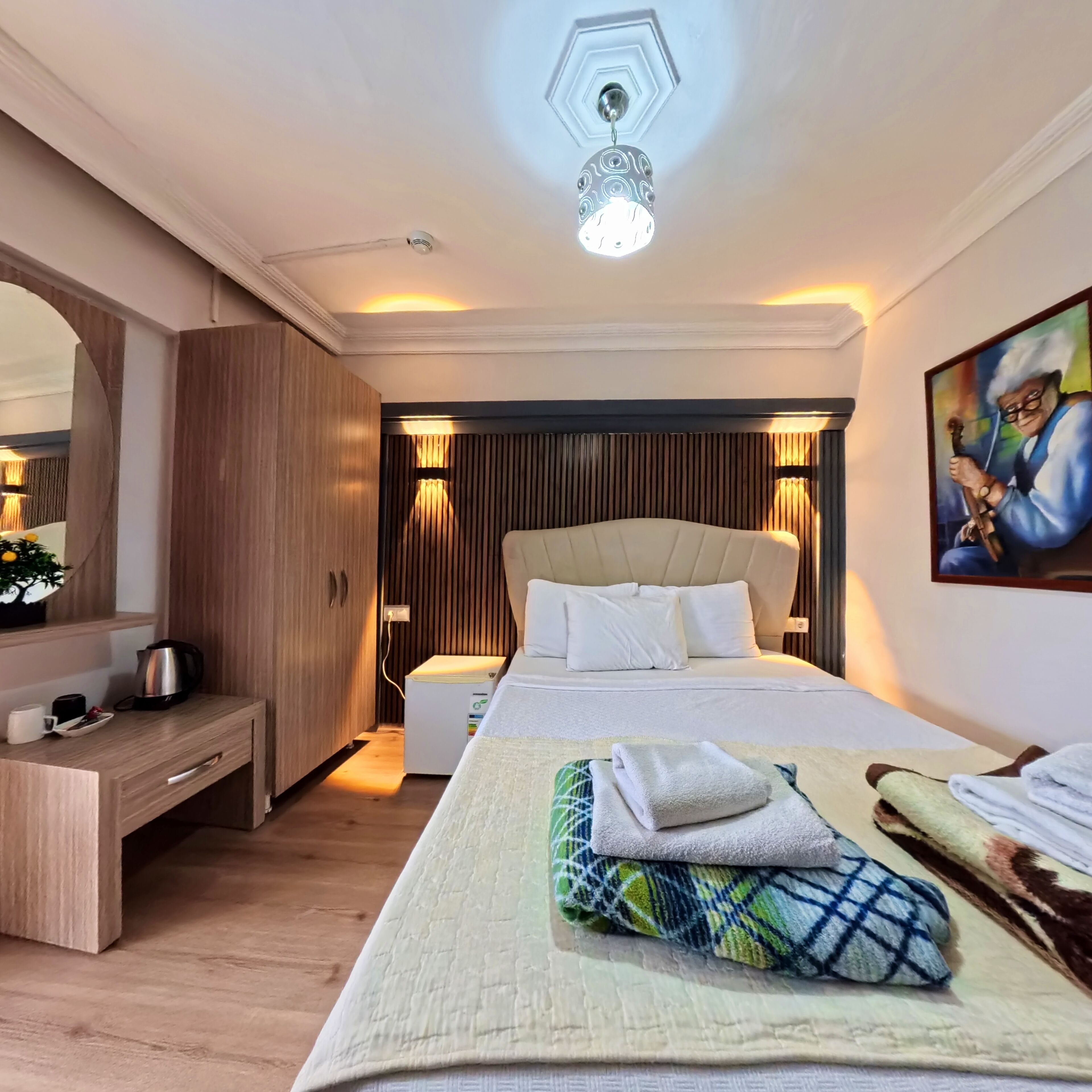 Ein Hotelzimmer mit einem Bett, einem Nachttisch, einer Lampe und einem Bild an der Wand.