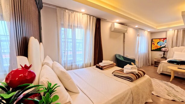 Una habitación de hotel moderna con una cama grande, un escritorio, un equipo de aire acondicionado y un cuadro en la pared.