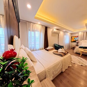 A modern hotel room with a large bed, a desk, an air conditioning unit, and a painting on the wall. - Alida Hotel (Denizli)