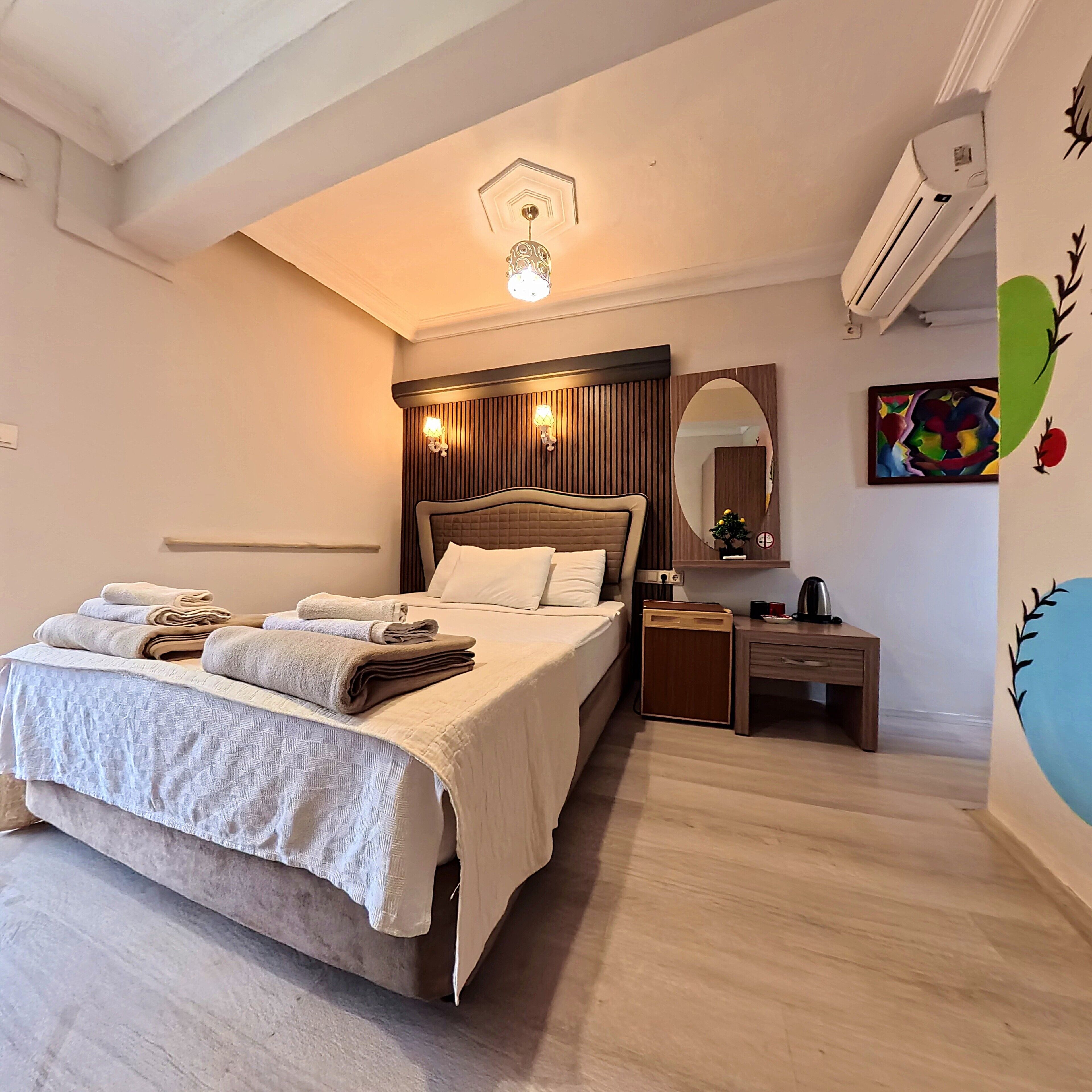 Une chambre à coucher comprenant un lit, une table de chevet, un miroir et des œuvres d’art murales.