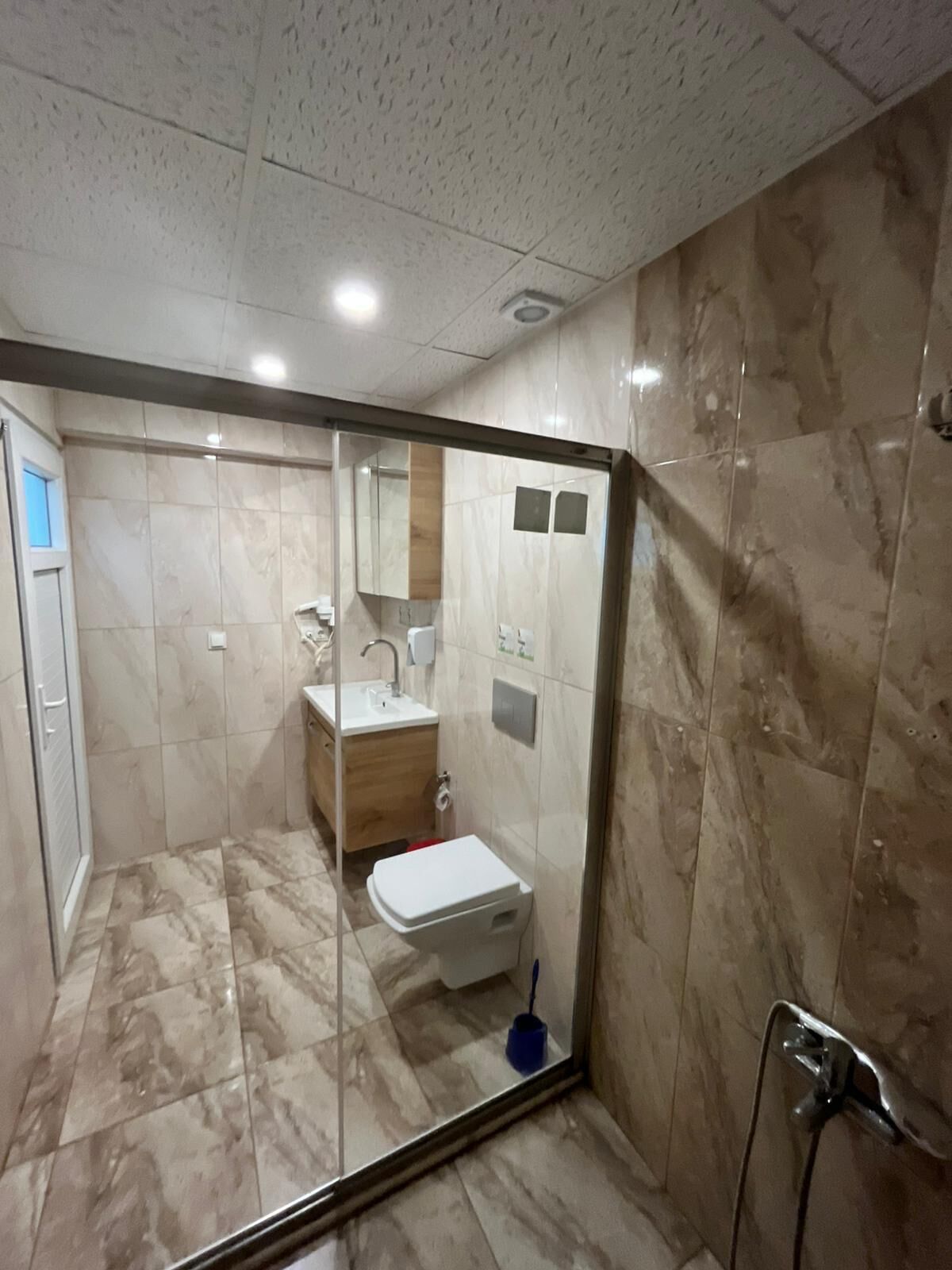 A bathroom with a shower, toilet, sink, and mirror.