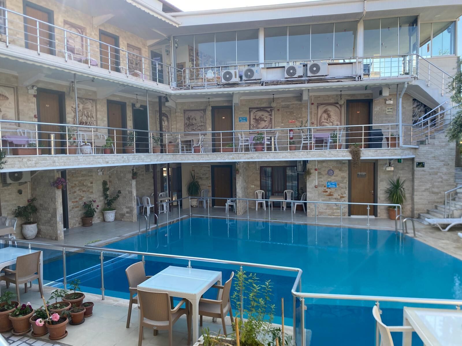 A multi-level hotel with a central pool, outdoor seating, and balconies.