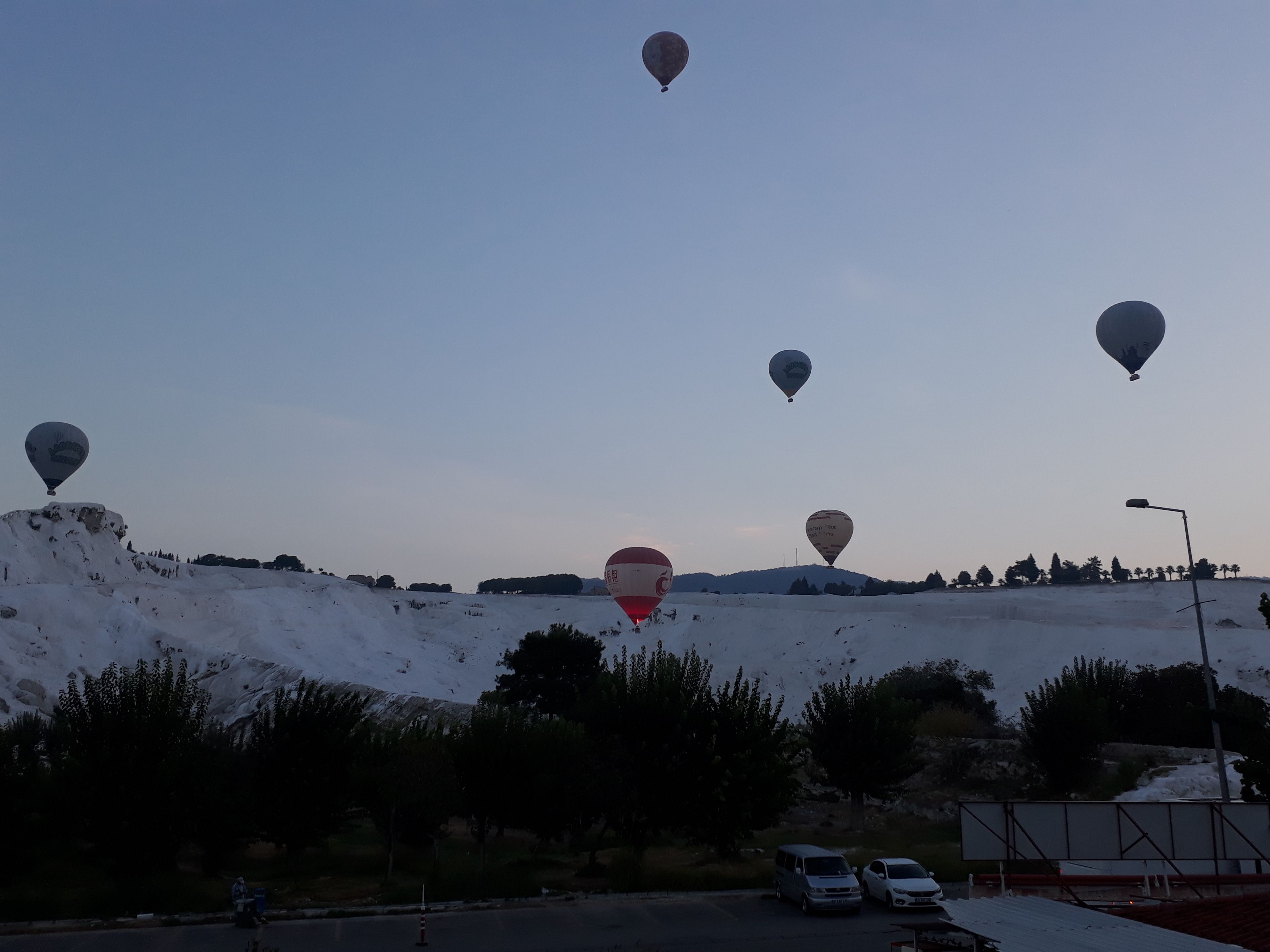 A snowy landscape with several hot air balloons in the sky.