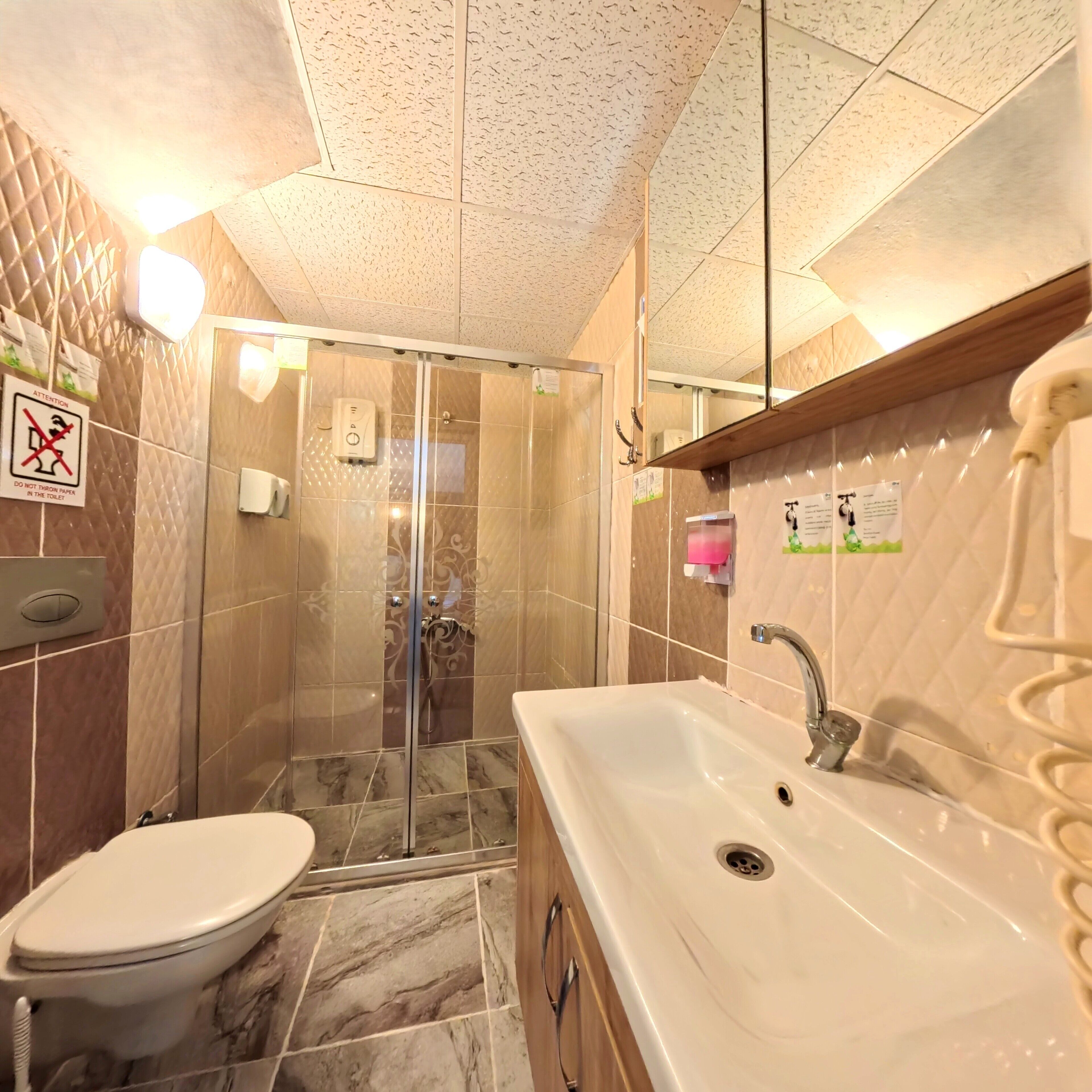 Une salle de bain comprenant des toilettes, un lavabo et un espace douche.