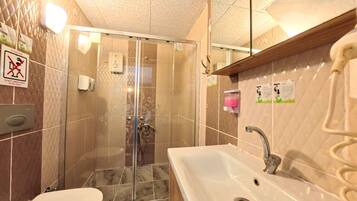 Une salle de bain comprenant des toilettes, un lavabo et un espace douche.