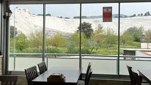 Un área de comedor con mesa y sillas, vista a un paisaje blanco a través de amplias ventanas, y un cartel de 'No Smoking'.