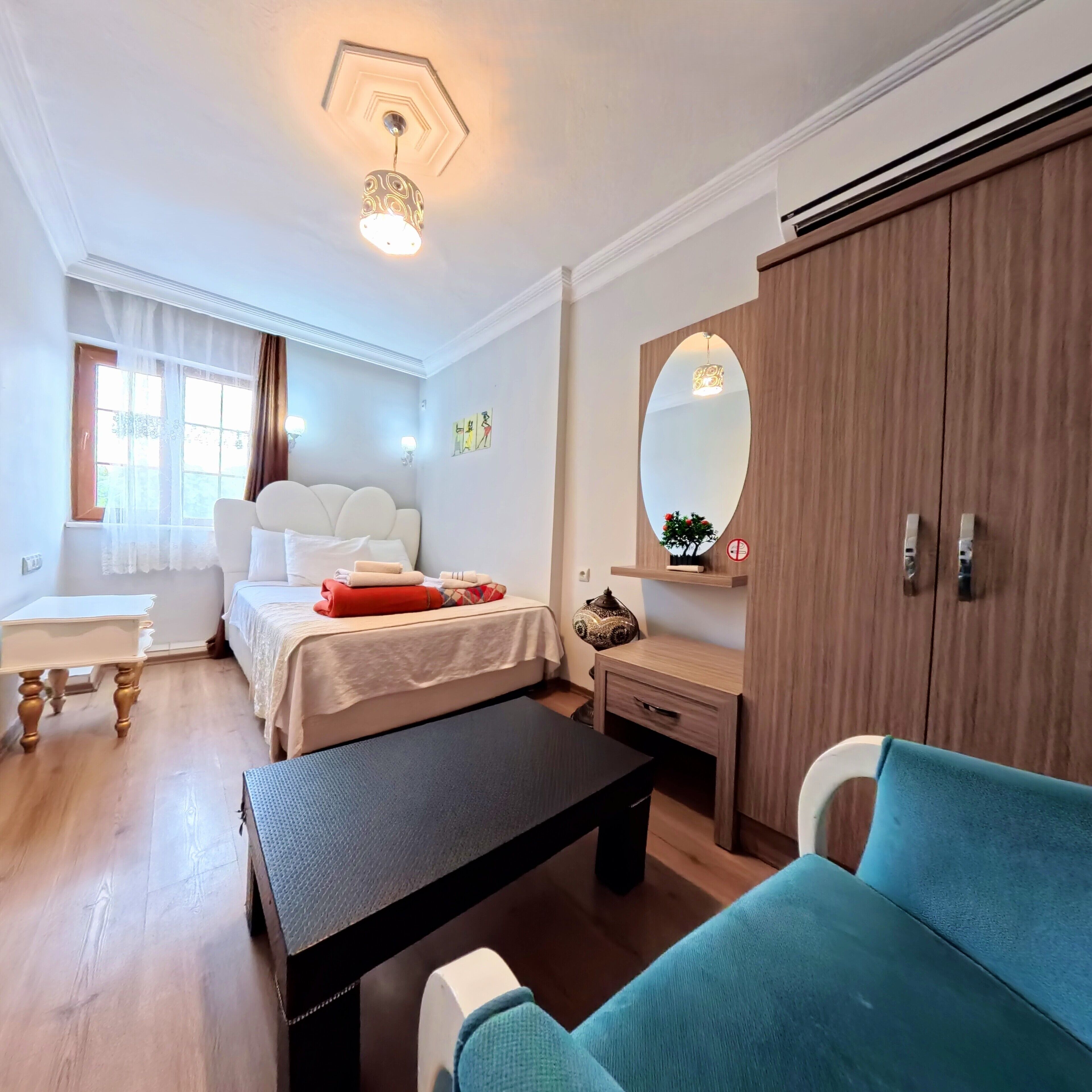 Una habitación de hotel con cama, escritorio, sofá, espejo y armario.