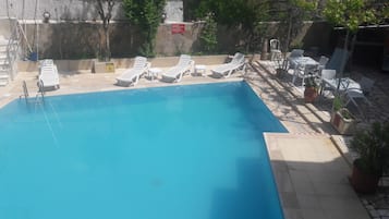 Una piscina al aire libre, sombrillas, sillones reclinables de piscina