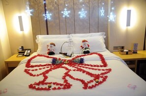 A hotel room with a bed adorned with red rose petals forming a heart shape, two Santa Claus figurines, and star-shaped lights on the wall. - Lavande Hotel Gz Yangji Metro Station Branch (Guangzhou)