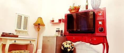 A compact kitchen with a refrigerator, microwave, and a small table with a chair.